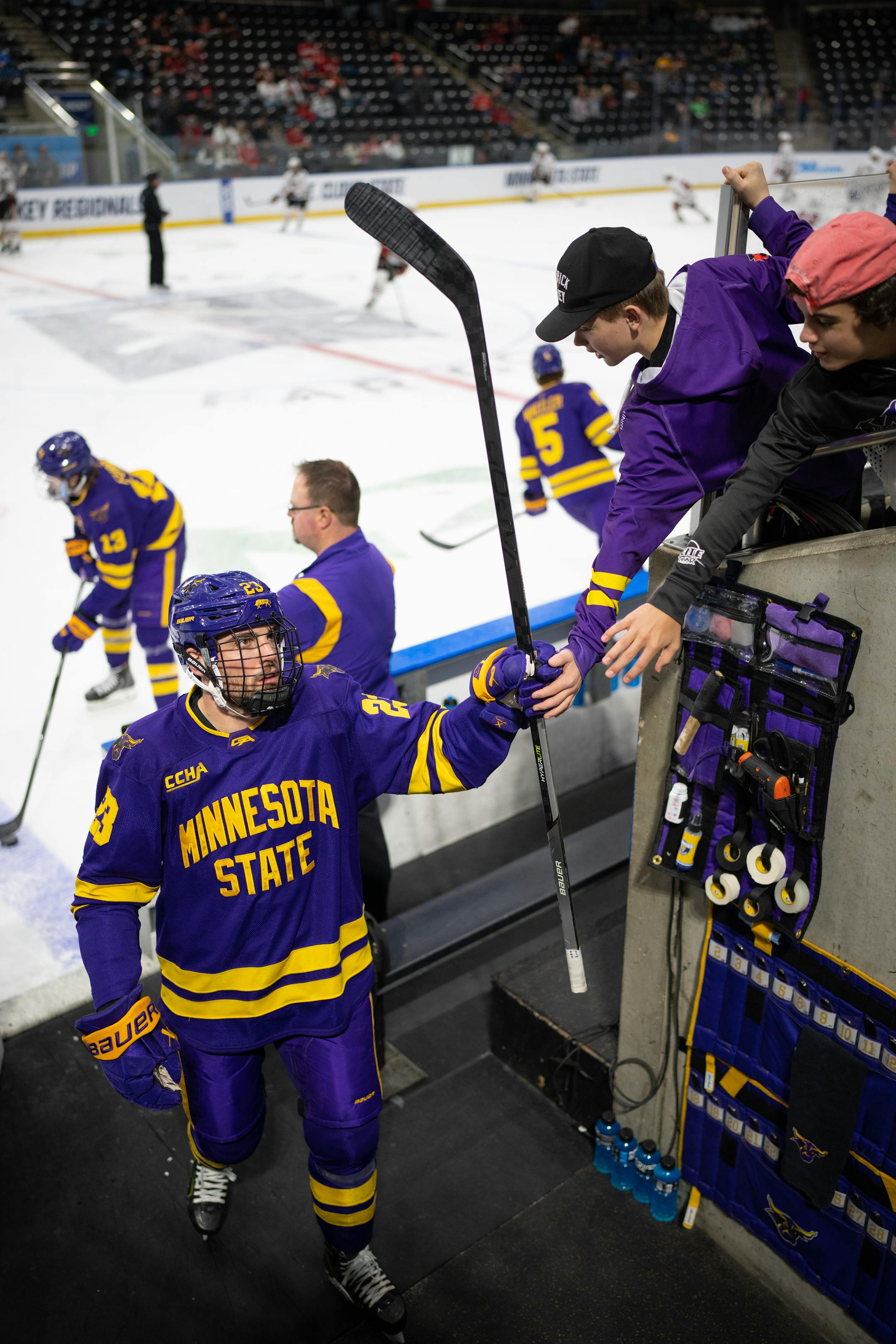 Minnesota State Mavericks defenseman Jake Livingstone (23) touched gloves with Jacob Johnson and Ashton Lotton, right, of Mankato as he came off the ice after warming up before the game.