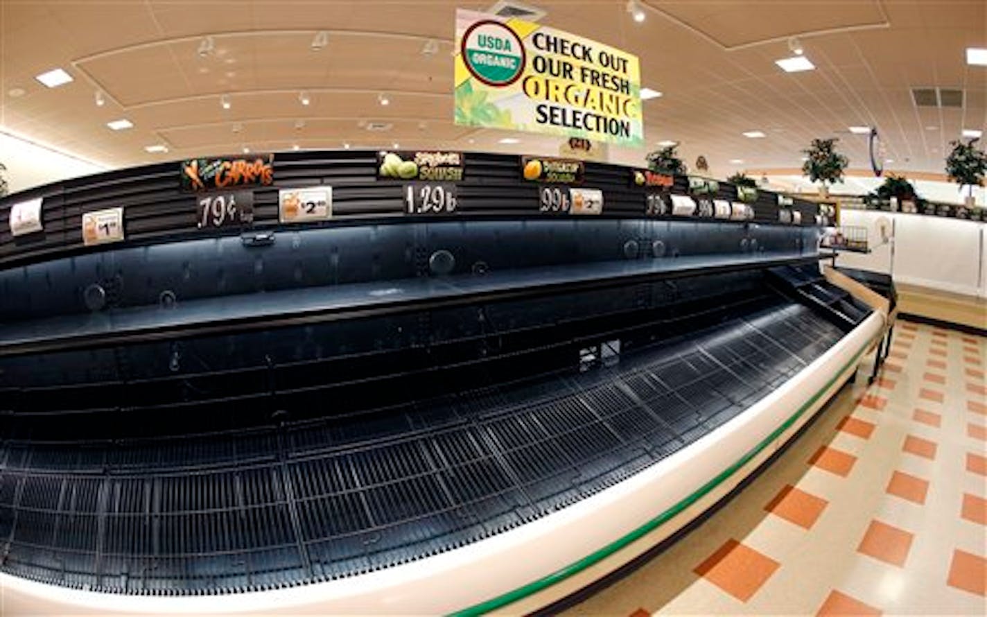 In this photo made with a fisheye lens, a sign sits atop empty produce shelves at Market Basket in Haverhill, Mass., Monday, Aug. 18, 2014. As an employee revolt at the New England grocery store chain headed into its fifth week, the governors of Massachusetts and New Hampshire made the unusual move of personally stepping into negotiations aimed at ending a standoff threatening the future of the popular low-priced supermarkets. (AP Photo/Elise Amendola)