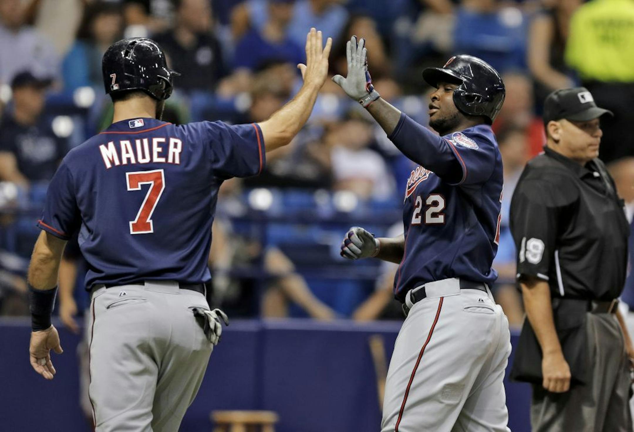 Minnesota Twins' Joe Mauer (7) and Miguel Sano (22) score on a single by Torii Hunter off Tampa Bay Rays starting pitcher Nathan Karns during the third inning of a baseball game Tuesday, Aug. 25, 2015, in St. Petersburg, Fla.