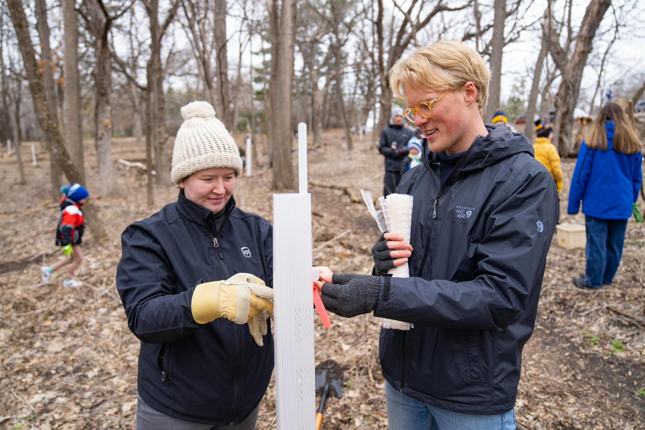 Allie Matney and Jacob Sevde Priesler, volunteers, tag a freshly planted elm tree as part of a tree planting event Saturday, April 22, 2023, on a Nature Hiking Trail leading to the Minnesota River in Bloomington.