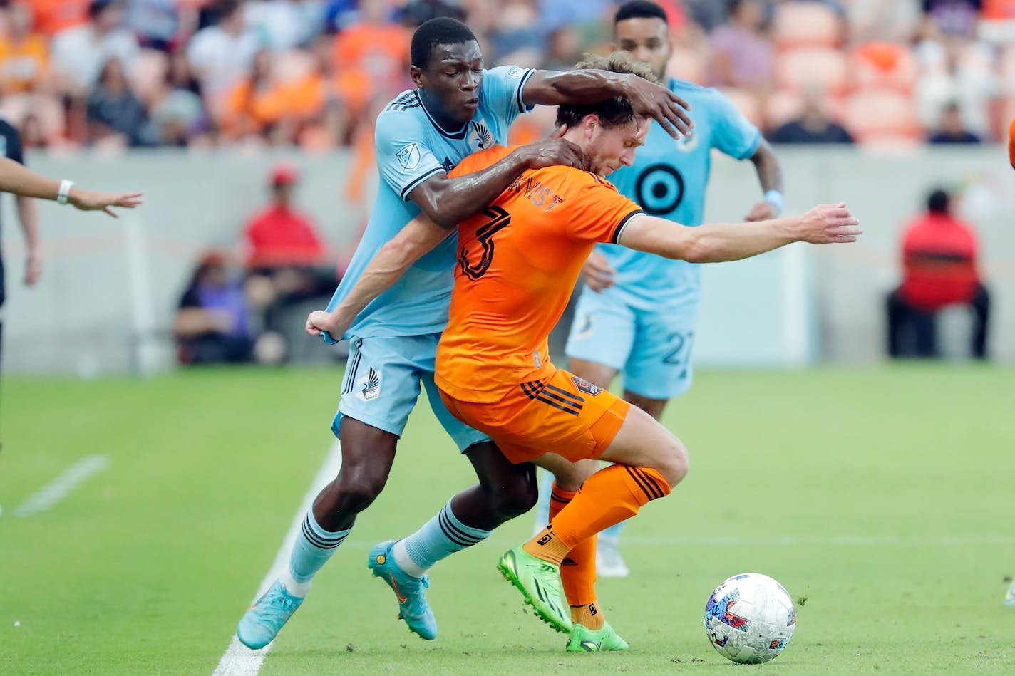 Minnesota United forward Bongokuhle Hlongwane, left, pulls on Houston Dynamo defender Adam Lundqvist, right, as he blocks out during the first half of an MLS soccer match Saturday, July 23, 2022, in Houston. (AP Photo/Michael Wyke)