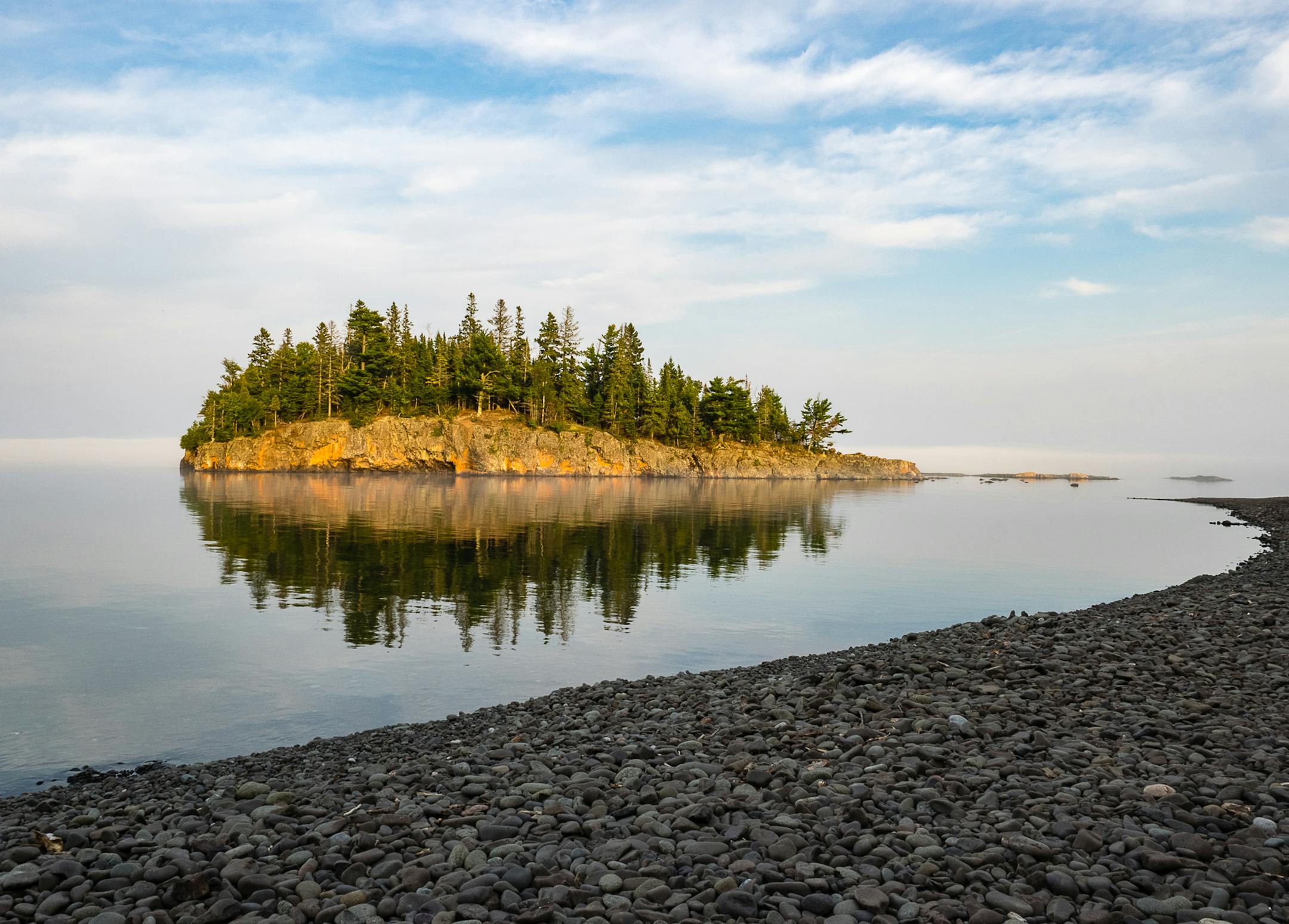 The Photographer: Maribeth Lundeen of Stillwater. The scene: The waning sun cast a gentle glow on a Lake Superior island when Lundeed took her camera to Split Rock Lighthouse State Park last August. ìPhotographers often go to this bay to take photos of the lighthouse as it catches the color of the sunset. When I arrived I liked the light on the island and I could see a blanket of low-lying fog moving in to shore. I guess it is not always about the lighthouse,î she wrote in an e-mail. v