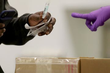 A person at a new saliva testing center for COVID-19 in the Minneapolis Convention Center dropped a saliva sample into a collection box.