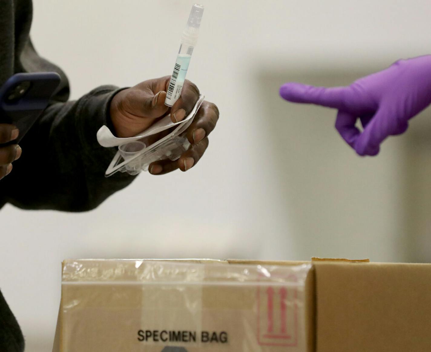 A person at a new saliva testing center for COVID-19 in the Minneapolis Convention Center dropped a saliva sample into a collection box.