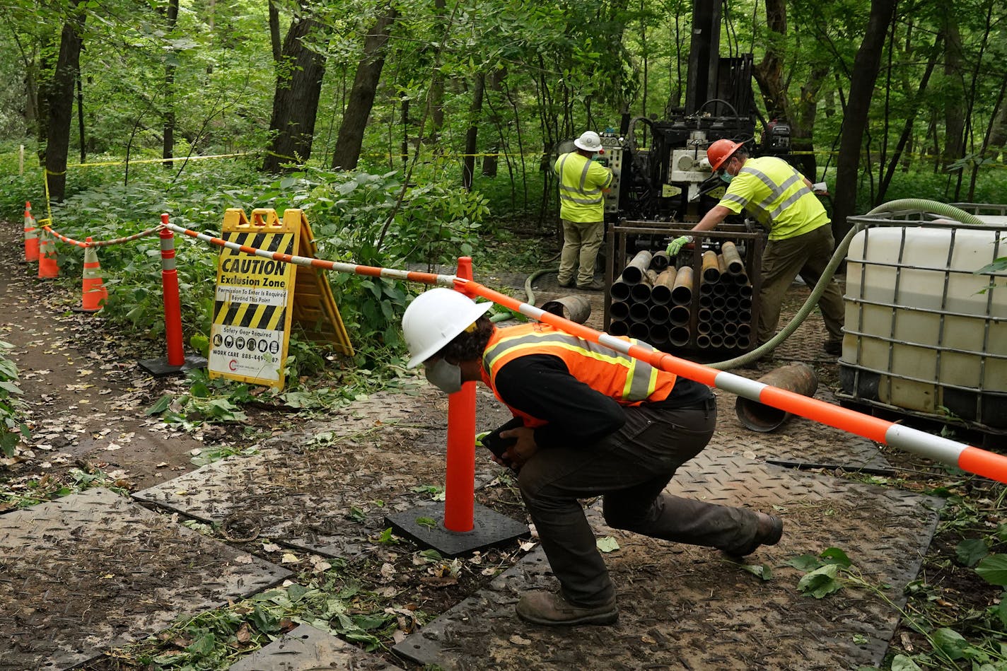 Kevin Havlicek, an environmental specialist with Arcadis, ducked under a barrier as crews from Cascade Drilling worked to drill a new monitoring well at Area C on the banks of the Mississippi River just below the Ford site redevelopment at the north end of Hidden Falls Regional Park Thursday. ] ANTHONY SOUFFLE • anthony.souffle@startribune.com Crews with Arcadis and Cascade Drilling worked to drill a new monitoring well at Area C on the banks of the Mississippi River just below the Ford site red