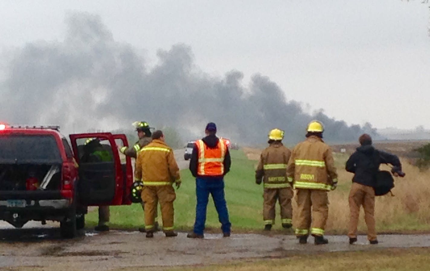 Emergency personnel watch as smoke rises in the background past a field after a BNSF Railway oil train derailed and caught fire in a rural area about two miles from Heimdal, N.D.. Wednesday, May 6, 2015. The central North Dakota town had to been evacuated due to the derailment and fire. (Tom Stromme/The Bismarck Tribune via AP)