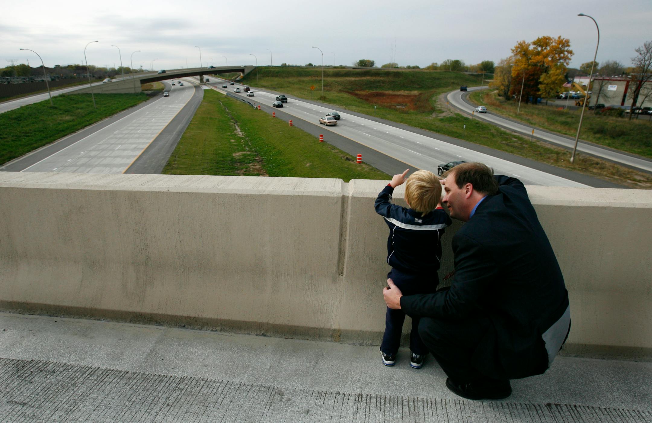 Michael Jacobson, 3, stood on the Lebore Road bridge with his father, Carl Jacobson, and watched traffic on Interstate 694 near Interstate 35E after a news conference atop the bridge to celebrate completion of an approximately 3-mile stretch of road.