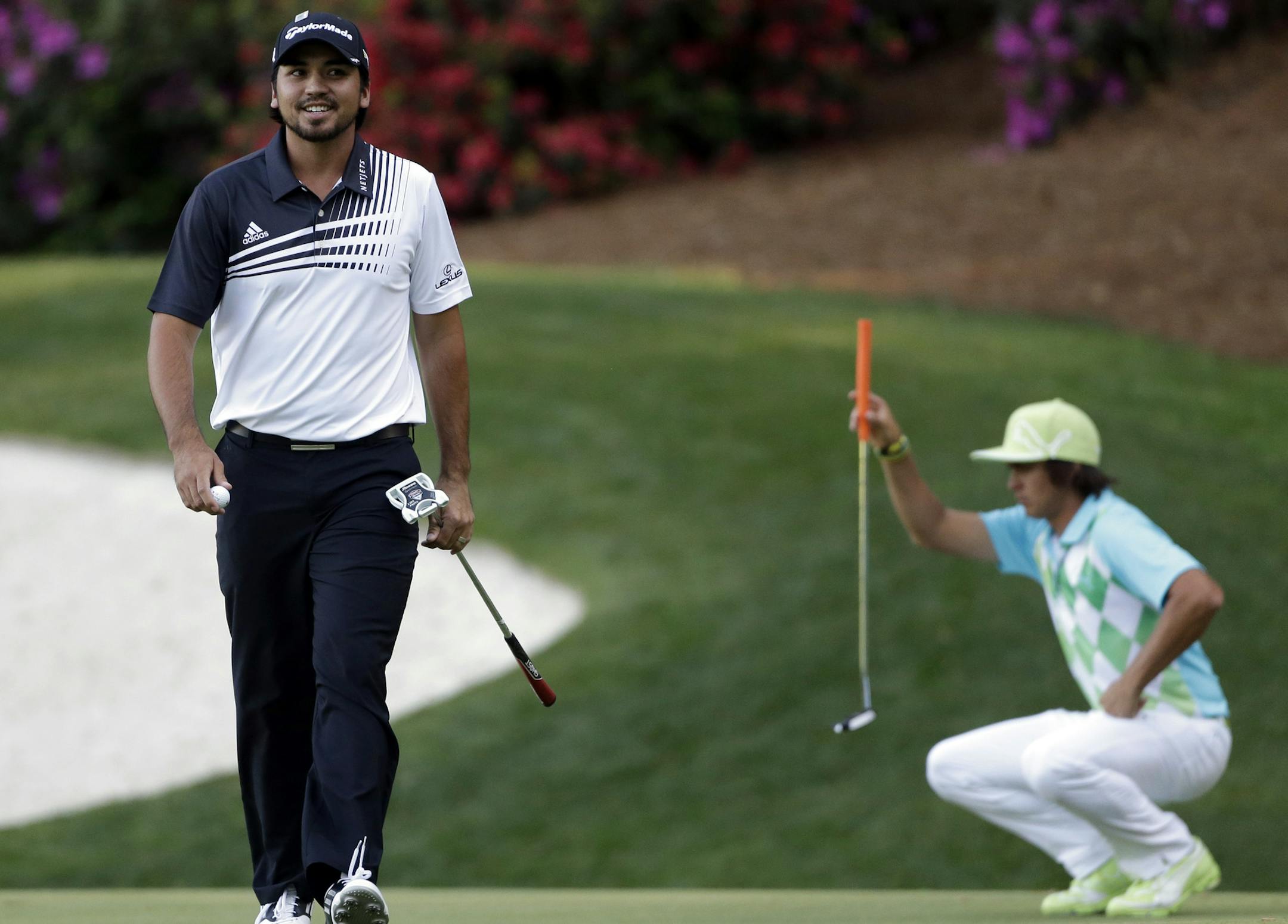 Rickie Fowler, right, lines up his putt as Jason Day, of Australia, walks off the 13th green during the second round of the Masters