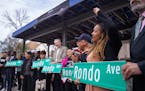 Council Member Anika Bowie and former Council Member Russel Balenger (far right) hold up “Rondo Ave” signs as part of a ceremony renaming the fron