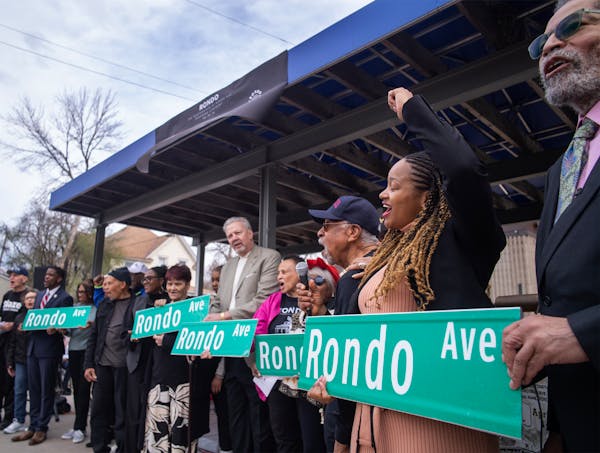 Council Member Anika Bowie and former Council Member Russel Balenger, far right, hold up “Rondo Ave” signs as part of a ceremony renaming the fron