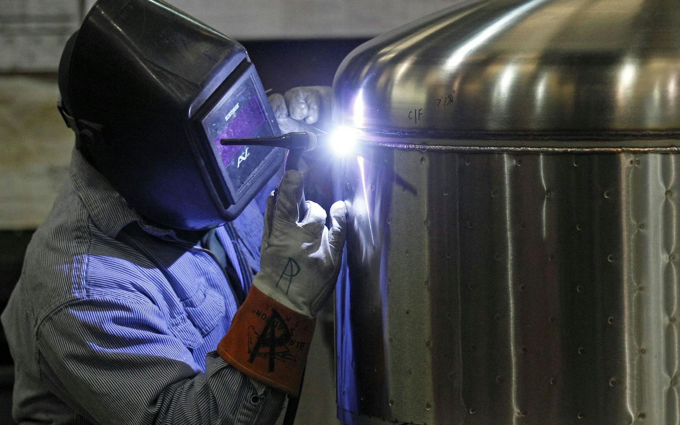In this Dec. 14, 2011 photo, Kevin Offield makes a weld on a tank at JV Northwest, in Canby, Ore. JV Northwest manufactures stainless steel vessels. The number of people applying for unemployment benefits dropped to its lowest level since April 2008, continuing a downward trend that reflects a strengthening job market. (AP Photo/Rick Bowmer) ORG XMIT: MIN2013070816254380