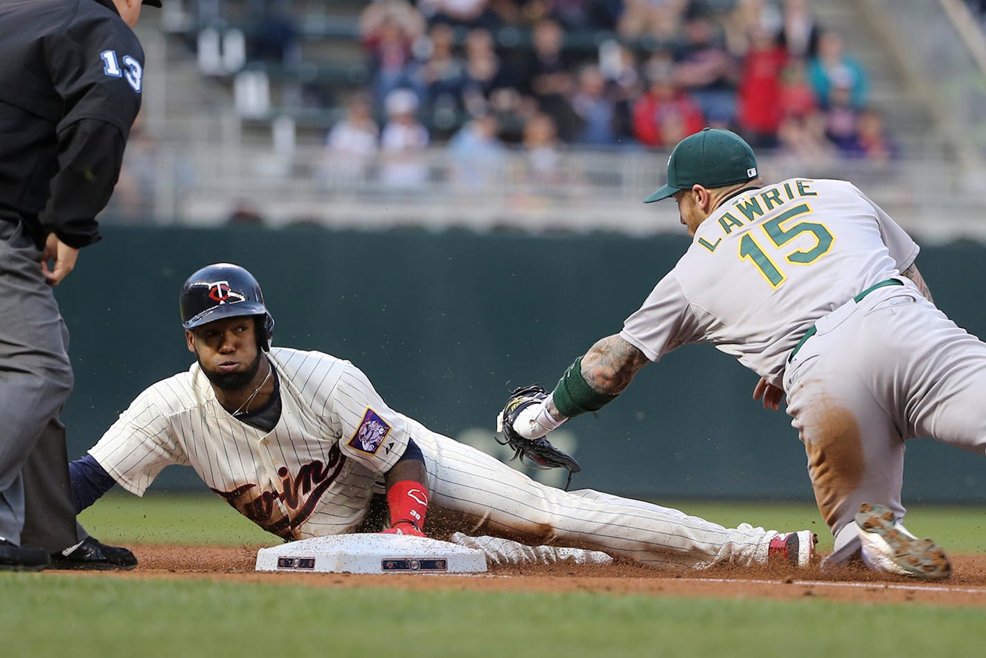 Danny Santana slide into third past Oakland's Brett Lawrie after he tripled in the bottom of the third.