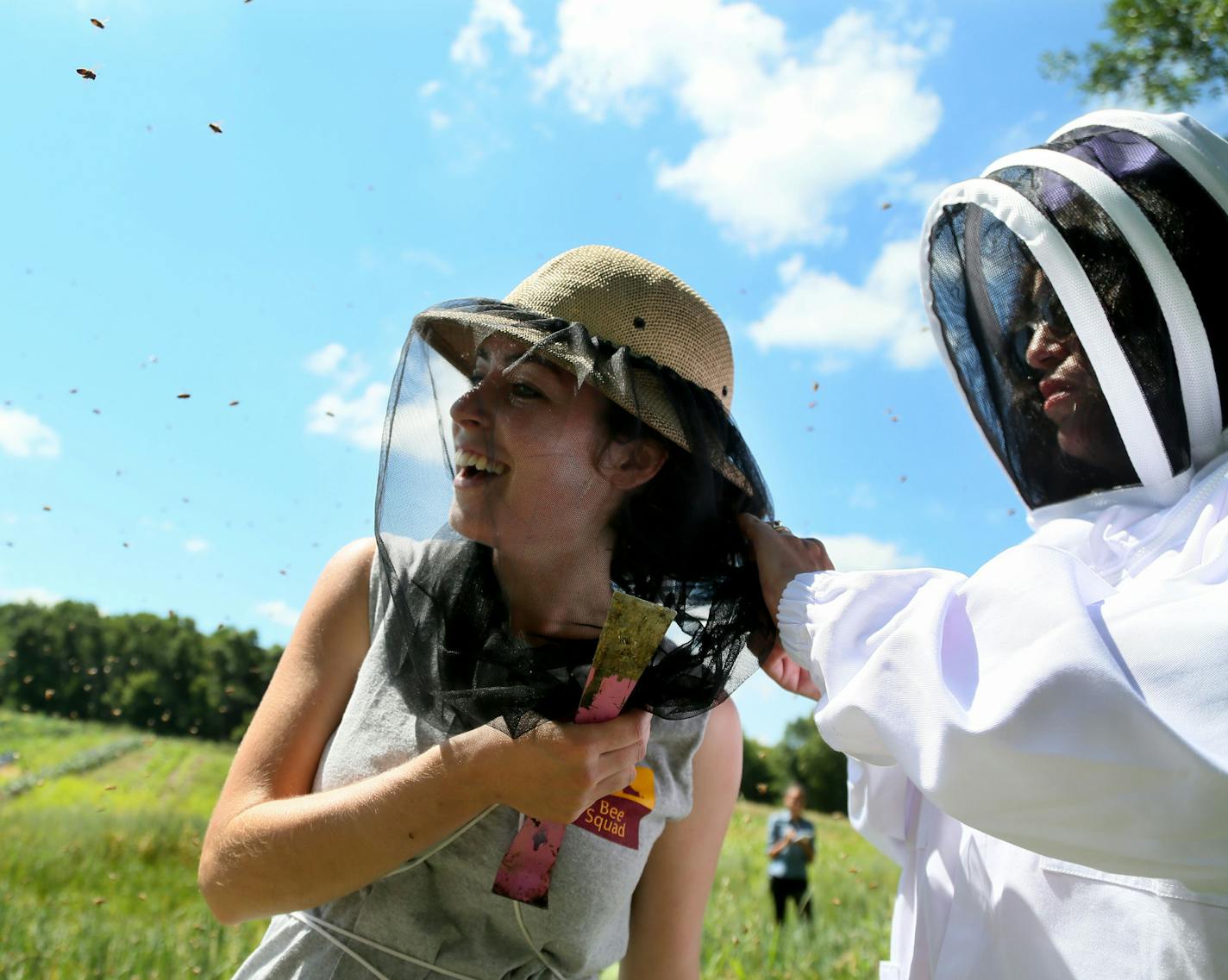 Reinas de Miel consists of five women and one youth who work at the hives every Thursday, including Thursday, July 23, 2015, at a farm in Lakeville, MN. Here, Bridget Mendel, University of Minnesota bee squad bee keeper and mentor to the group, gets an assist from Susana Espinosa de Sygulla, right, in getting a bee out of her hair that had managed to get underneath her netting. Urban Ventures has partnered with the University of Minnesota to train low-income women to become beekeepers.](DAVID JO