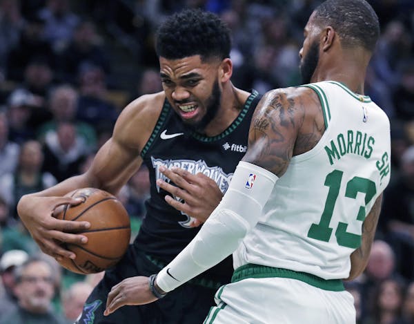Minnesota Timberwolves center Karl-Anthony Towns, left, grimaces as he collides with Boston Celtics forward Marcus Morris (13) during the first quarte