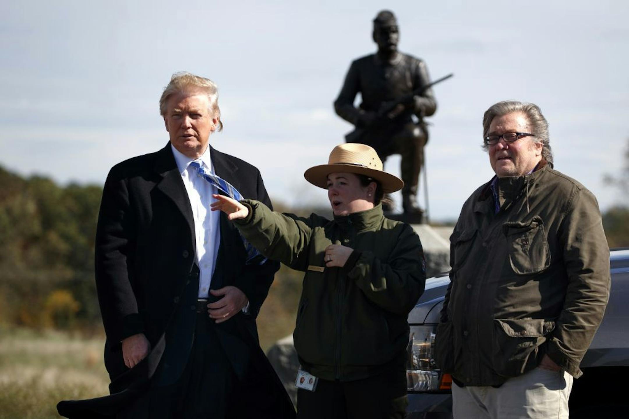 Interpretive park ranger Caitlin Kostic, center, gives a tour near the high-water mark of the Confederacy at Gettysburg National Military Park to Republican presidential candidate Donald Trump, left, and campaign CEO Steve Bannon, Saturday, Oct. 22, 2016, in Gettysburg, Pa.