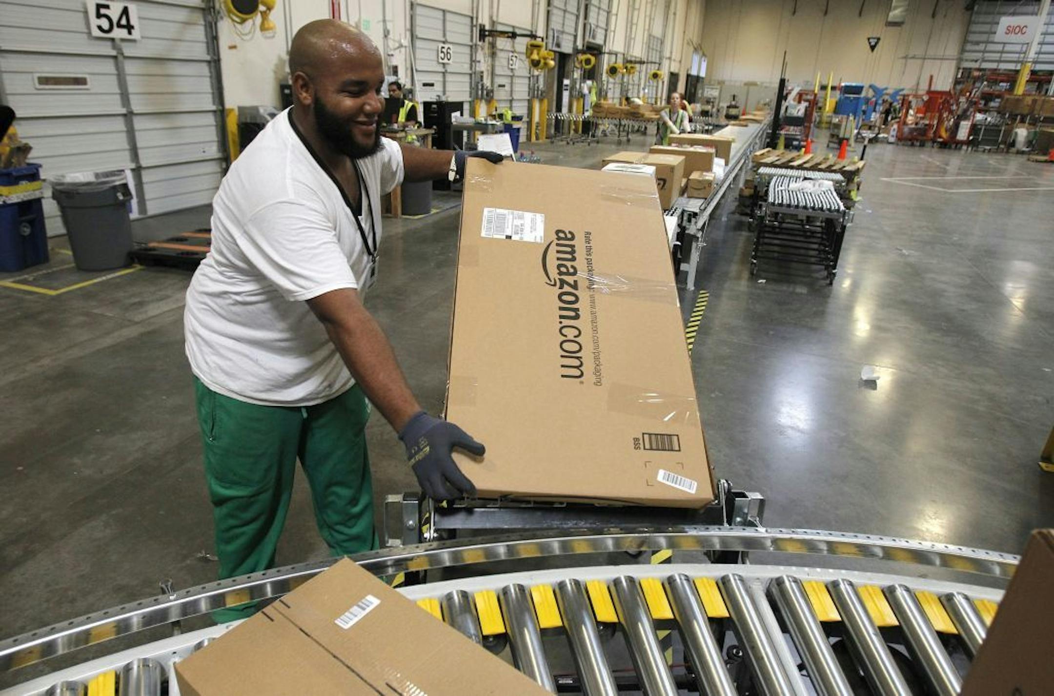 FILE - In this Nov. 11, 2010 file photo, Leacroft Green places a package to the correct shipping area at an Amazon.com fulfillment center, in Goodyear, Ariz. Amazon is teaming up with the U.S. Postal Service to deliver packages on Sundays. The Seattle company said Monday, Nov. 11, 2013, that Sunday delivery will be available this week to customers in the New York and Los Angeles metropolitan areas. Amazon and the Postal Service plan to roll out service to "a large portion of the U.S. population"