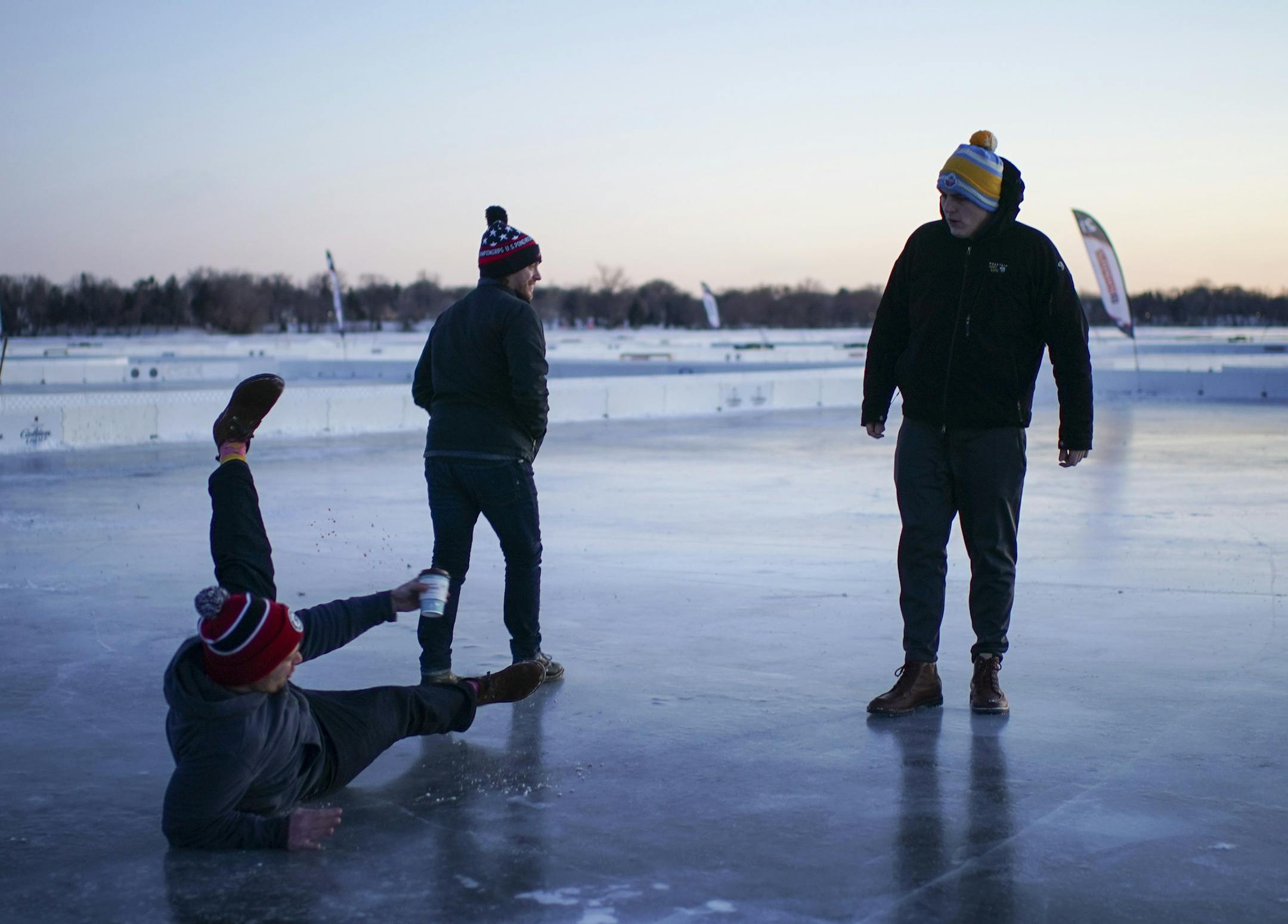 Collin McCullough spilled just a few drops of his coffee when he slipped on the ice while checking out one of the pond hockey rinks with Nick Lazenby, and Jordan Ricks, right. The three, all from Kansas City, are playing in the tournament. ] JEFF WHEELER • jeff.wheeler@startribune.com Single digit temperatures and bitter a wind chill curtailed the planned kickoff to the U.S. Pond Hockey tournament at Lake Nokomis Thursday night, January 24, 2019. However, a few hardy souls couldn't resist