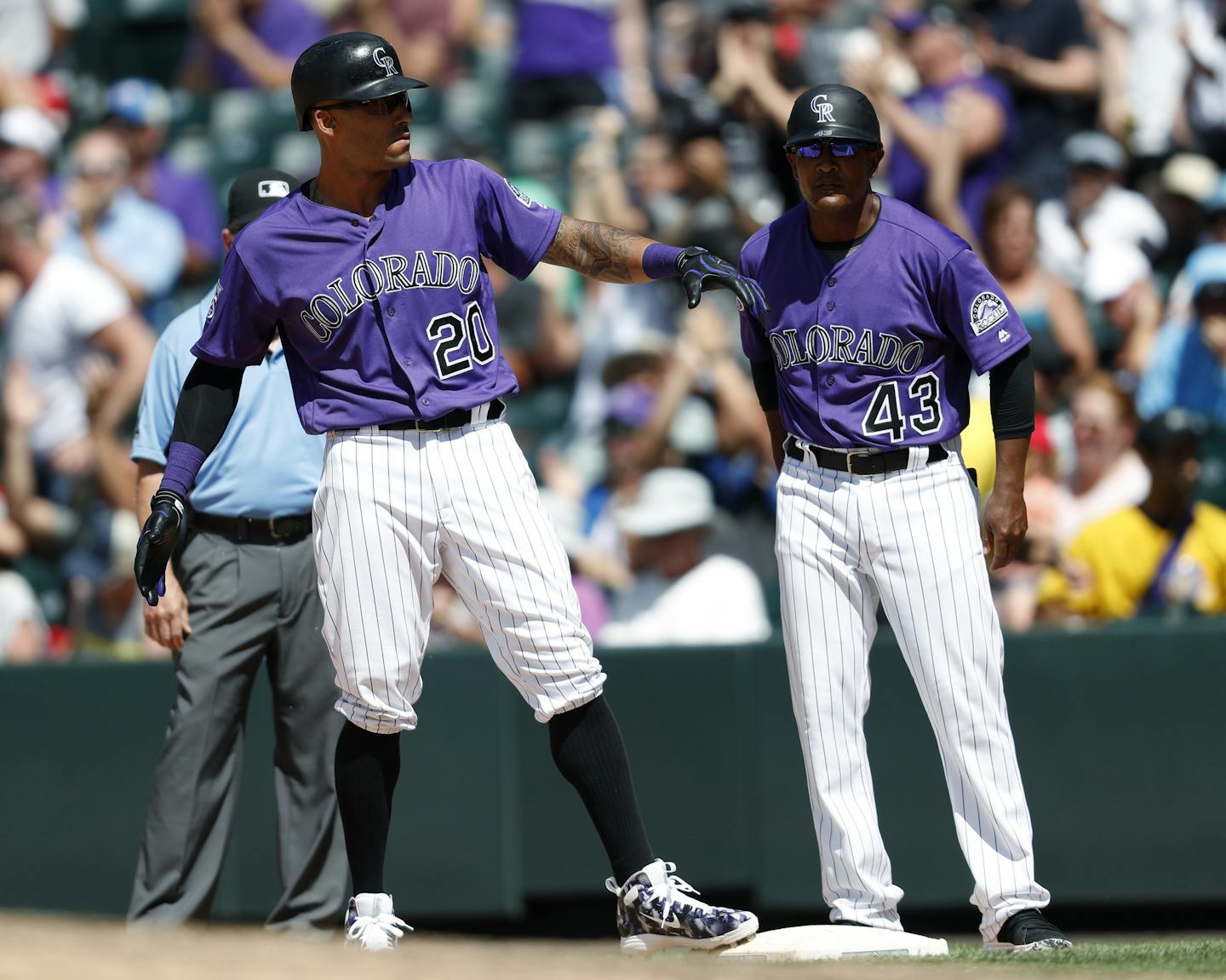 Colorado Rockies' Ian Desmond, left, celebrates as first base coach Tony Diaz looks on after Desmond drove in two runs on a single off Arizona Diamondbacks starting pitcher Zack Godley in the sixth inning of a baseball game Sunday, June 10, 2018, in Denver. (AP Photo/David Zalubowski)