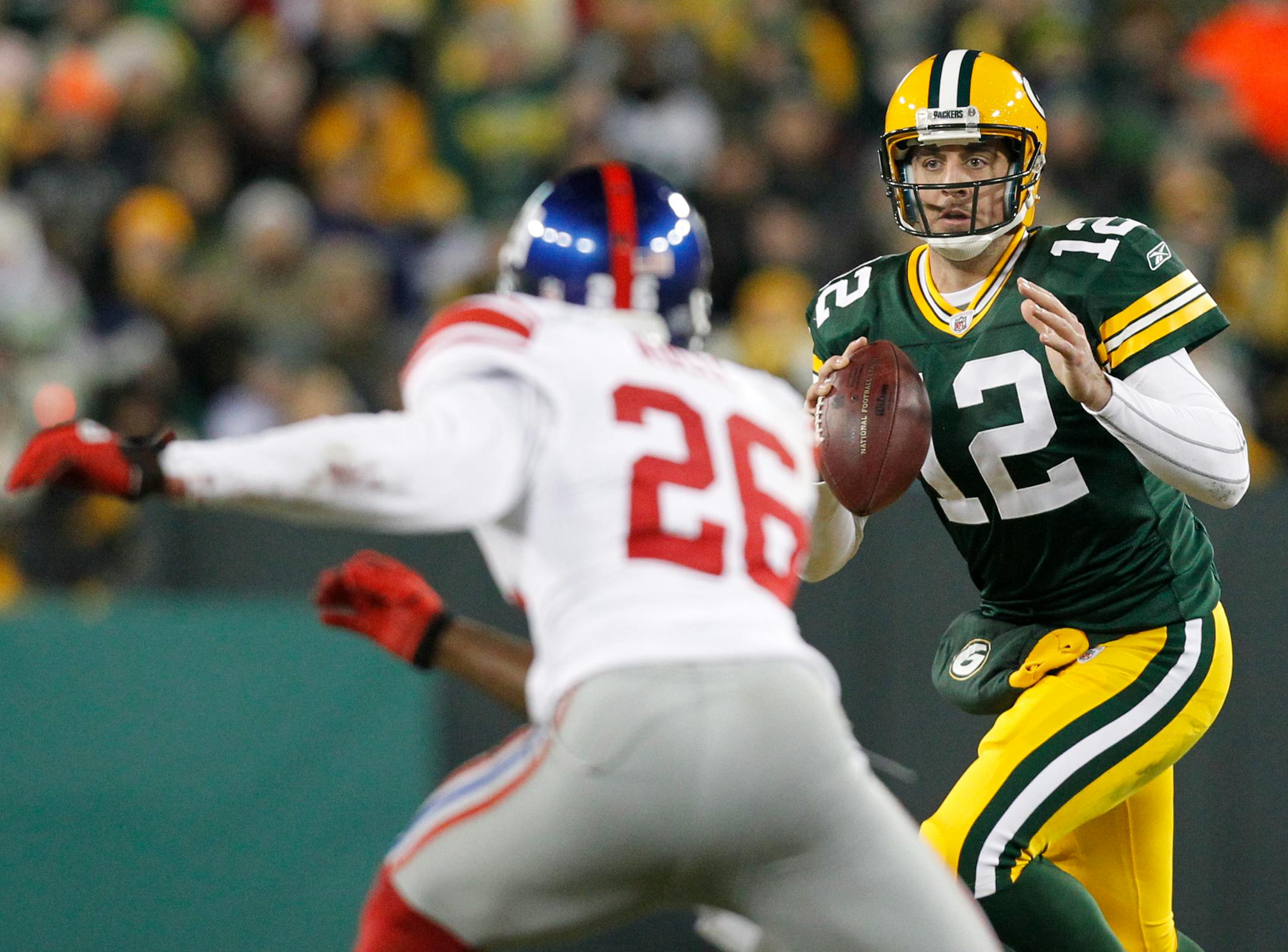 Green Bay Packers quarterback Aaron Rodgers (12) looks to pass in front of New York Giants safety Antrel Rolle (26) during the second half of an NFL football game Sunday, Dec. 26, 2010, in Green Bay