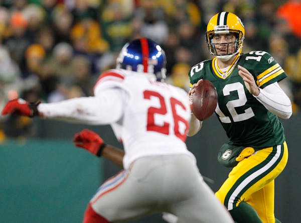 Green Bay Packers quarterback Aaron Rodgers (12) looks to pass in front of New York Giants safety Antrel Rolle (26) during the second half of an NFL f