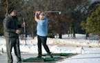 Mark Myhre, right, of Blaine, took advantage of the warm weather to practice his swing at the Bunker Hills Golf Club's driving range Thursday in Coon 