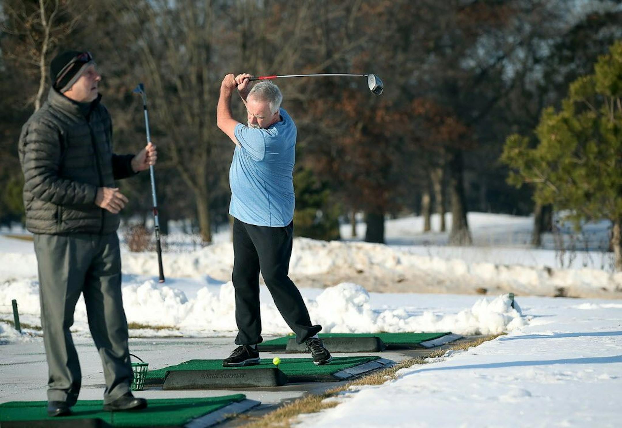 Mark Myhre, right, of Blaine, took advantage of the warm weather to practice his swing at the Bunker Hills Golf Club's driving range Thursday in Coon Rapids.
