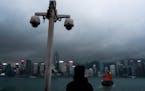 FILE - Surveillance cameras are seen as a visitor looks at Victoria Harbour in Hong Kong, Monday, March 11, 2024.