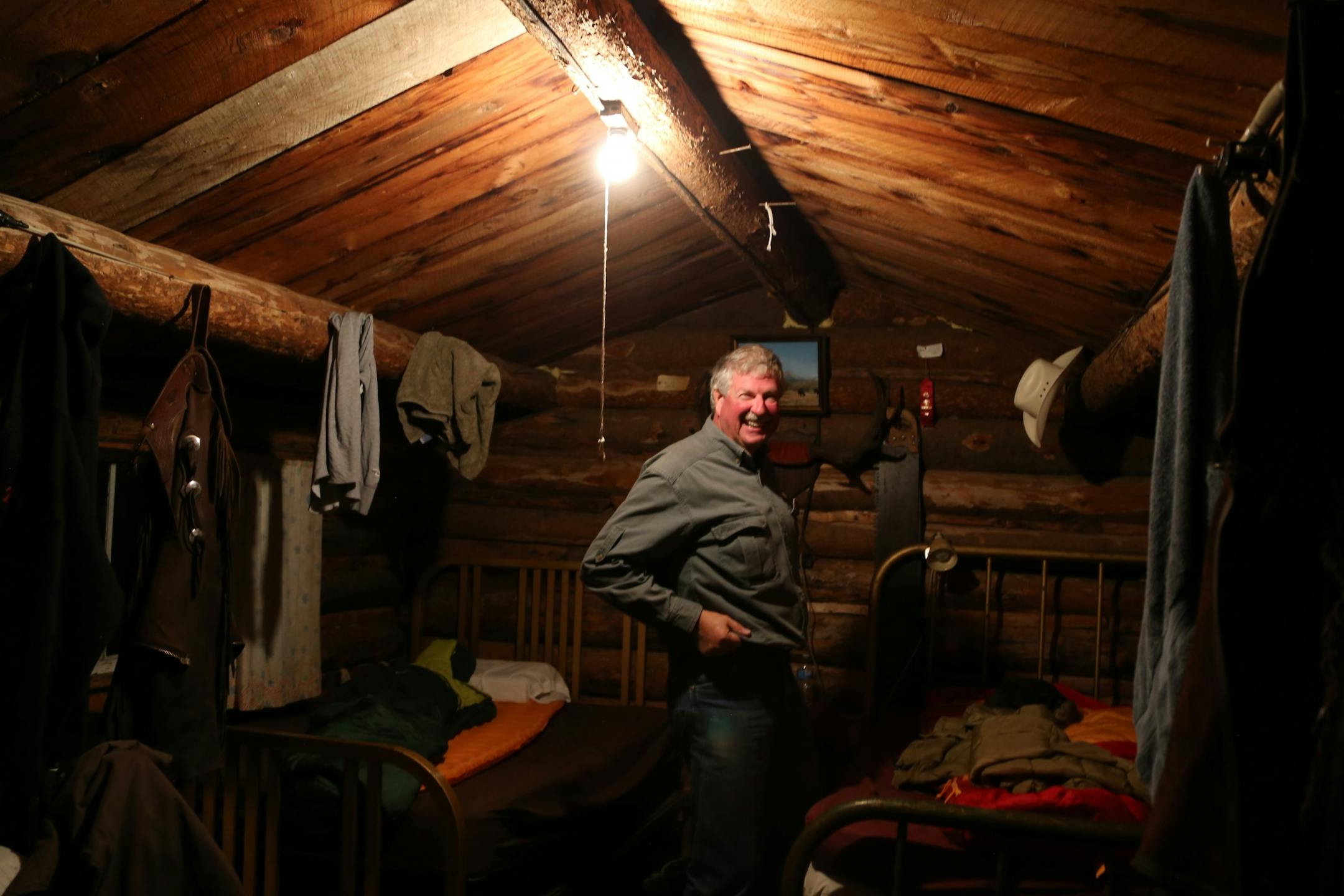 Dave Hamilton of the Twin Cities prepares for a welcome night's sleep in a small log cabin in the Montana mountains. Along with a dozen or so other riders on horseback, Hamilton spent the day rounding up cattle over 13,000 mountain acres and driving them to their wintering grounds in the valley below.