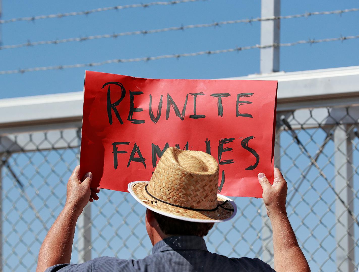 A protester holds a sign outside a closed gate at the Port of Entry facility, Thursday, June 21, 2018, in Fabens, Texas, where tent shelters are being used to house separated family members.