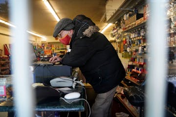 8th St. Market owner Woods Halley works to get the computer/cash register up and running for the 9 a.m. opening Friday, Jan. 21, 2022 in Minneapolis, 