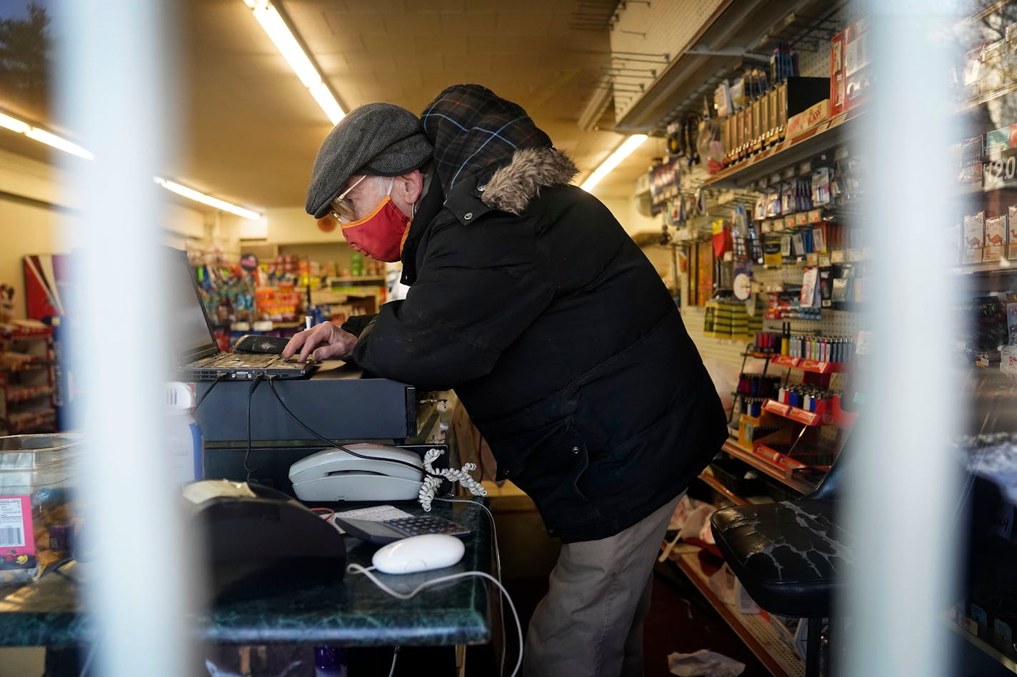 8th St. Market owner Woods Halley works to get the computer/cash register up and running for the 9 a.m. opening Friday, Jan. 21, 2022 in Minneapolis, Minn. 8th St. Market, which has metal bars on the front window, was robbed 6 times in November and Halley made the decision to only take credit/debit cards as a result so there isn't cash in the store. ] DAVID JOLES • david.joles@startribune.com