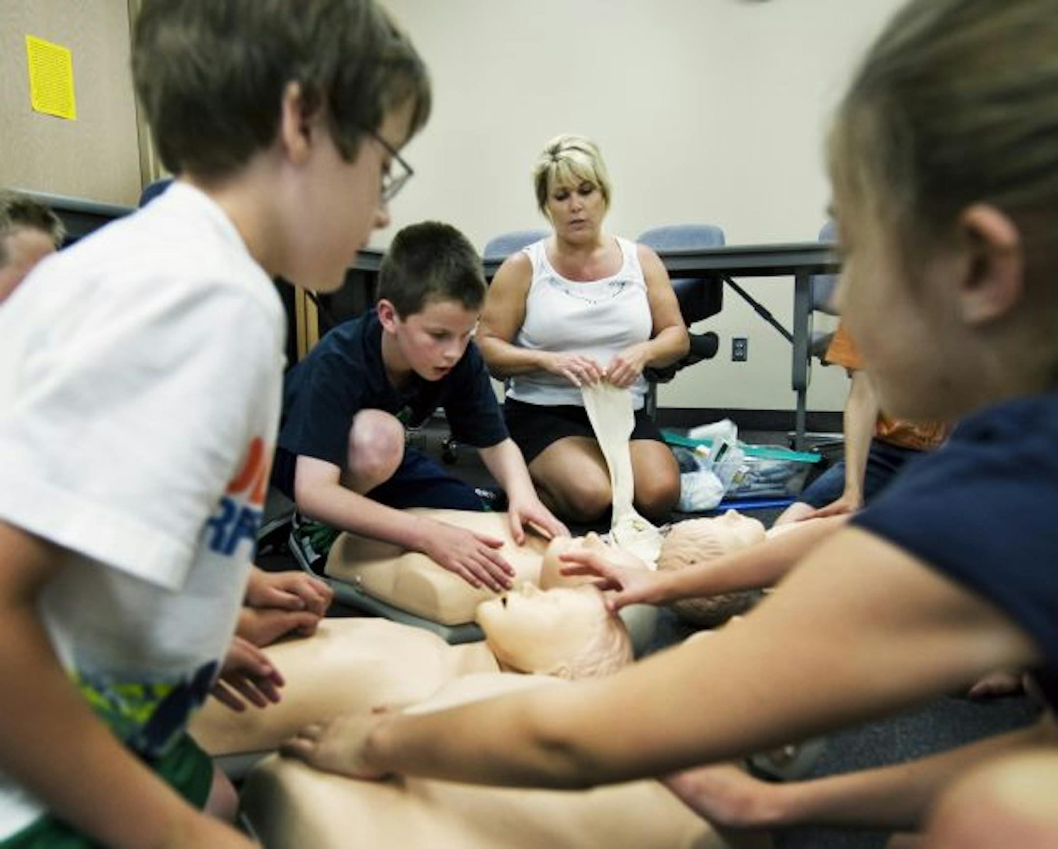 Instructor Sandra Pinski shows the class of kids, ages from 9 to 11 years old, how to do recitations maneuvers on practice dummies.