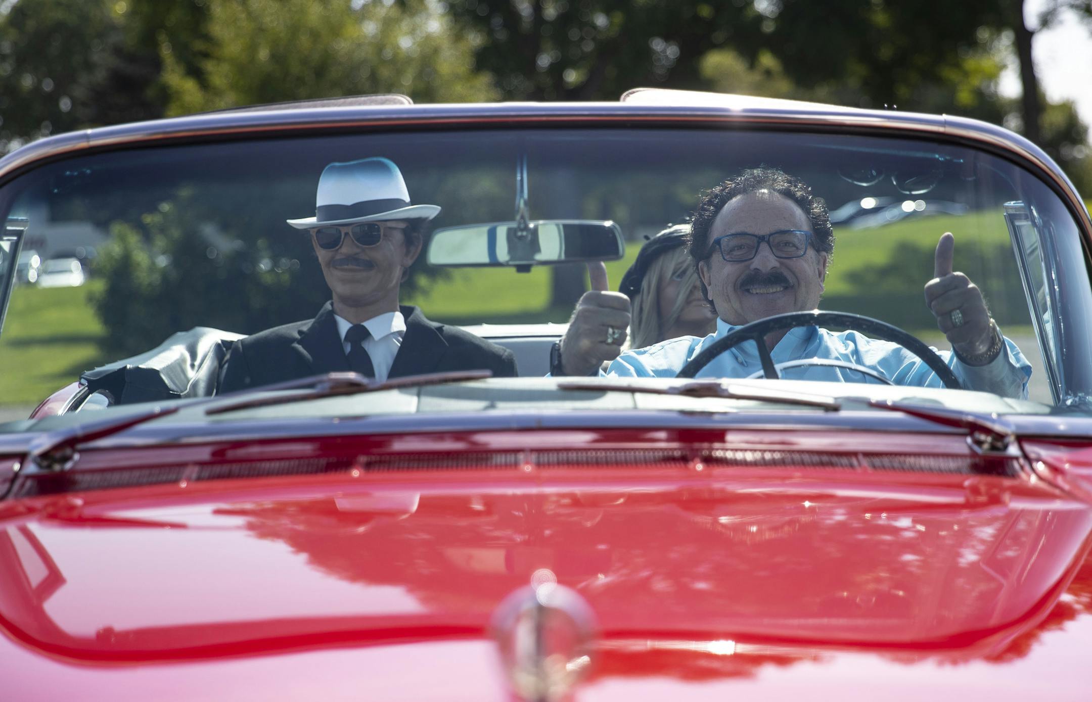 Super salesman Dick Enrico poses for a portrait in his antique Buick that he drives around town with wax models in the back dressed as gangsters.