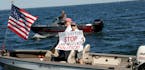 In this Saturday, July 8, 2017, photo provided by Mille Lacs Messenger, people on a boat encircle Minnesota Gov. Mark Dayton, not pictured, on Mille L