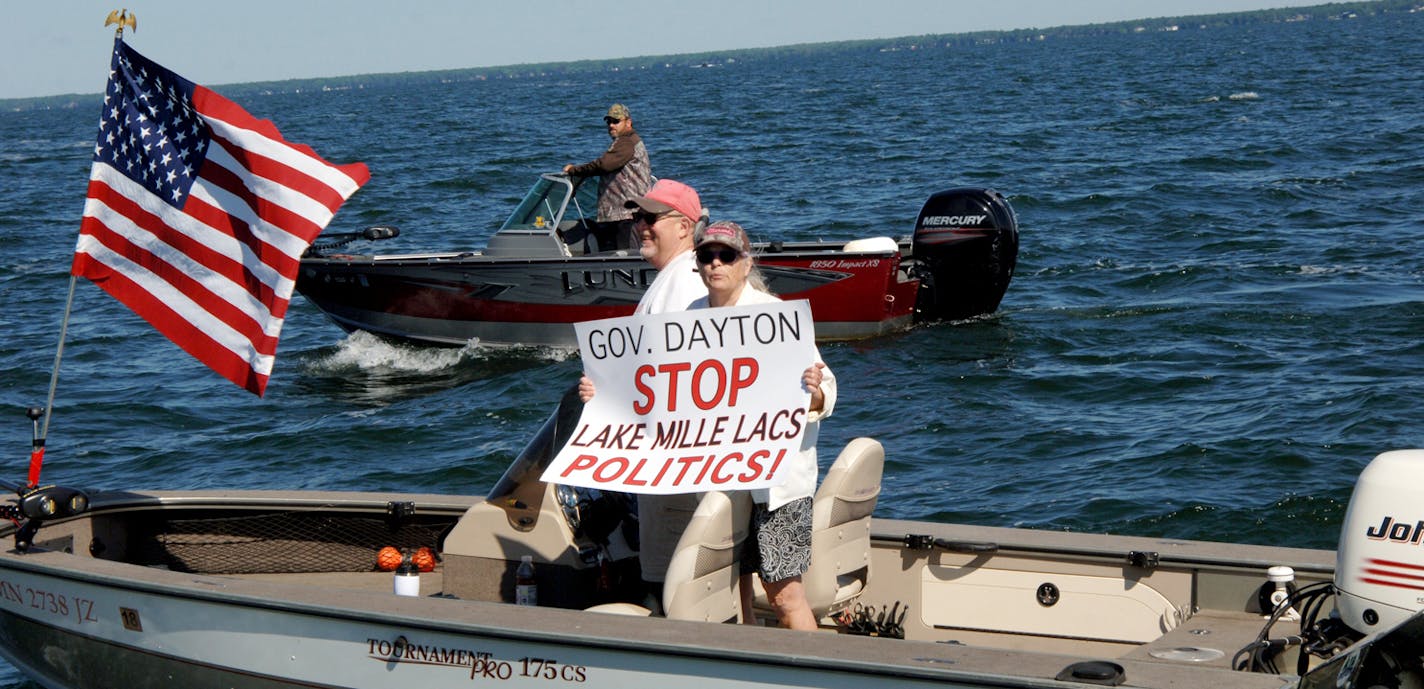 In this Saturday, July 8, 2017, photo provided by Mille Lacs Messenger, people on a boat encircle Minnesota Gov. Mark Dayton, not pictured, on Mille Lacs Lake to protest a temporary ban on walleye fishing in Minnesota. The Star Tribune reports that Dayton was with a group fishing for bass on the lake Saturday when dozens of protesters encircled him. (Vivian LaMoore/Mille Lacs Messenger via AP) ORG XMIT: MIN2017071018265132