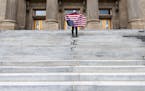 A student holding a U.S. flag upside down stands atop the steps at the Idaho Capitol building in Boise on April 26. The Idaho Senate has approved legi