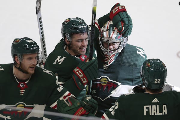 Minnesota Wild's Zach Parise celebrates with his arm around teammate goalie Alex Stalock after Stalock won the game 3-2 in a shootout against the Dall