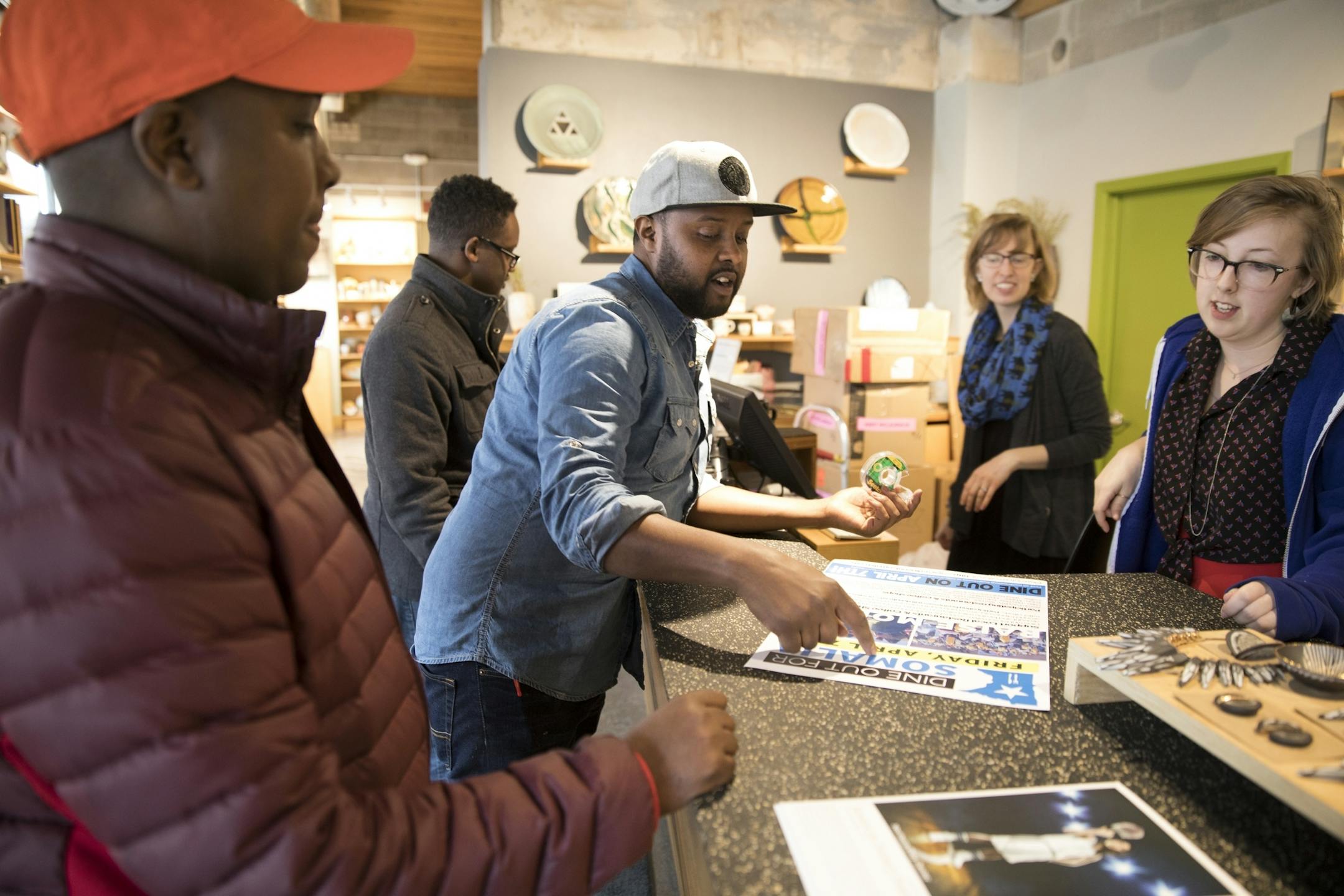 Abdirahman Kahin, from left, owner of Afro Deli, and Burhan Elmi, owner of Capitol Cafe, talk to Alison Beech and Alexa McAdams at neighboring business Northern Clay Center about putting up a sign advertising Dine Out for Somalia.