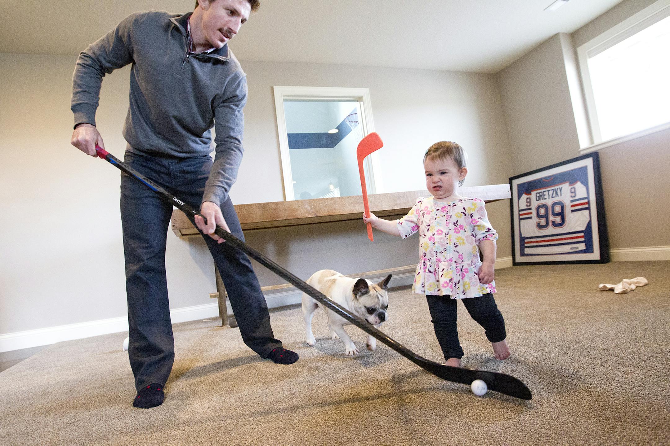 Minnesota Wild's Ryan Carter plays hockey with his daughter Natalie, 15 months, and their French bulldog Ruby at their home in Gem Lake November 22, 2015. (Courtney Perry/Special to the Star Tribune)