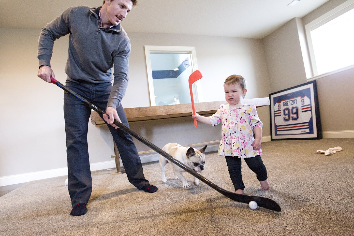 Minnesota Wild's Ryan Carter plays hockey with his daughter Natalie, 15 months, and their French bulldog Ruby at their home in Gem Lake November 22, 2015. (Courtney Perry/Special to the Star Tribune)