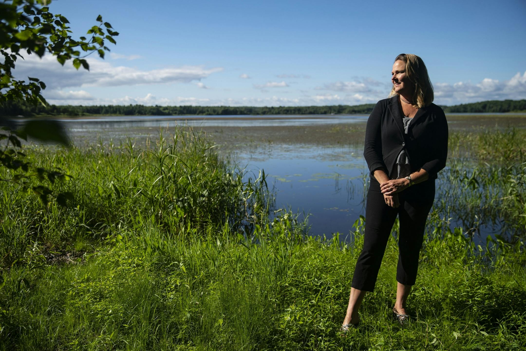 Lindi Mae Carlson posed for a portrait by Hay Lake near Carlton, less than two hours from the Twin Cities, on the edge of a lakeside property she recently sold to an out-of-state buyer.