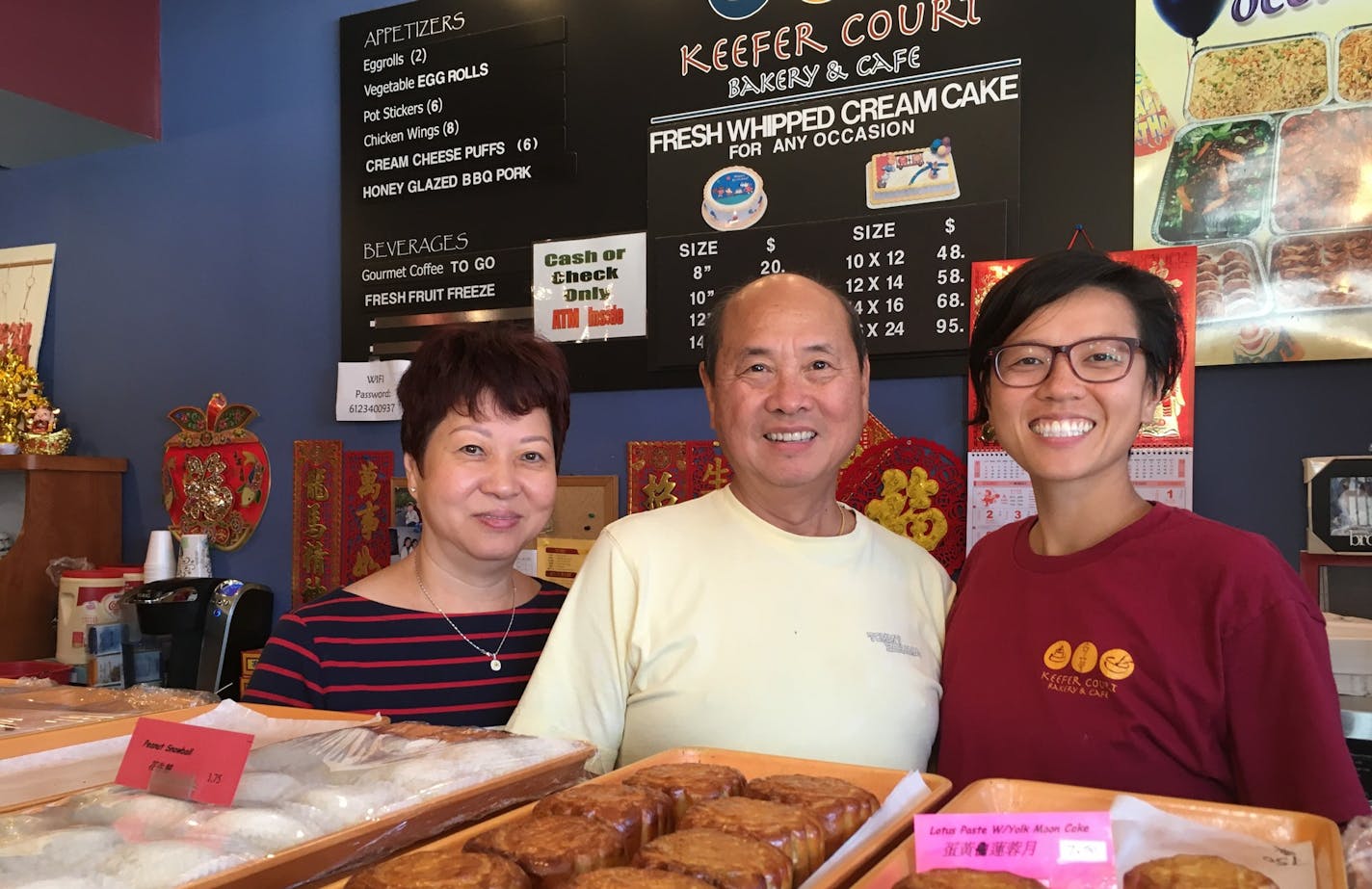 Pauline, Sunny and Michelle Kwan of Keefer Court Bakery & Cafe stand behind a tray of mooncakes. Sunny Kwan is planning to retire and his wife Pauline will work less frequently as daughter Michelle takes over one of the largest Chinese bakeries in the Twin Cities.