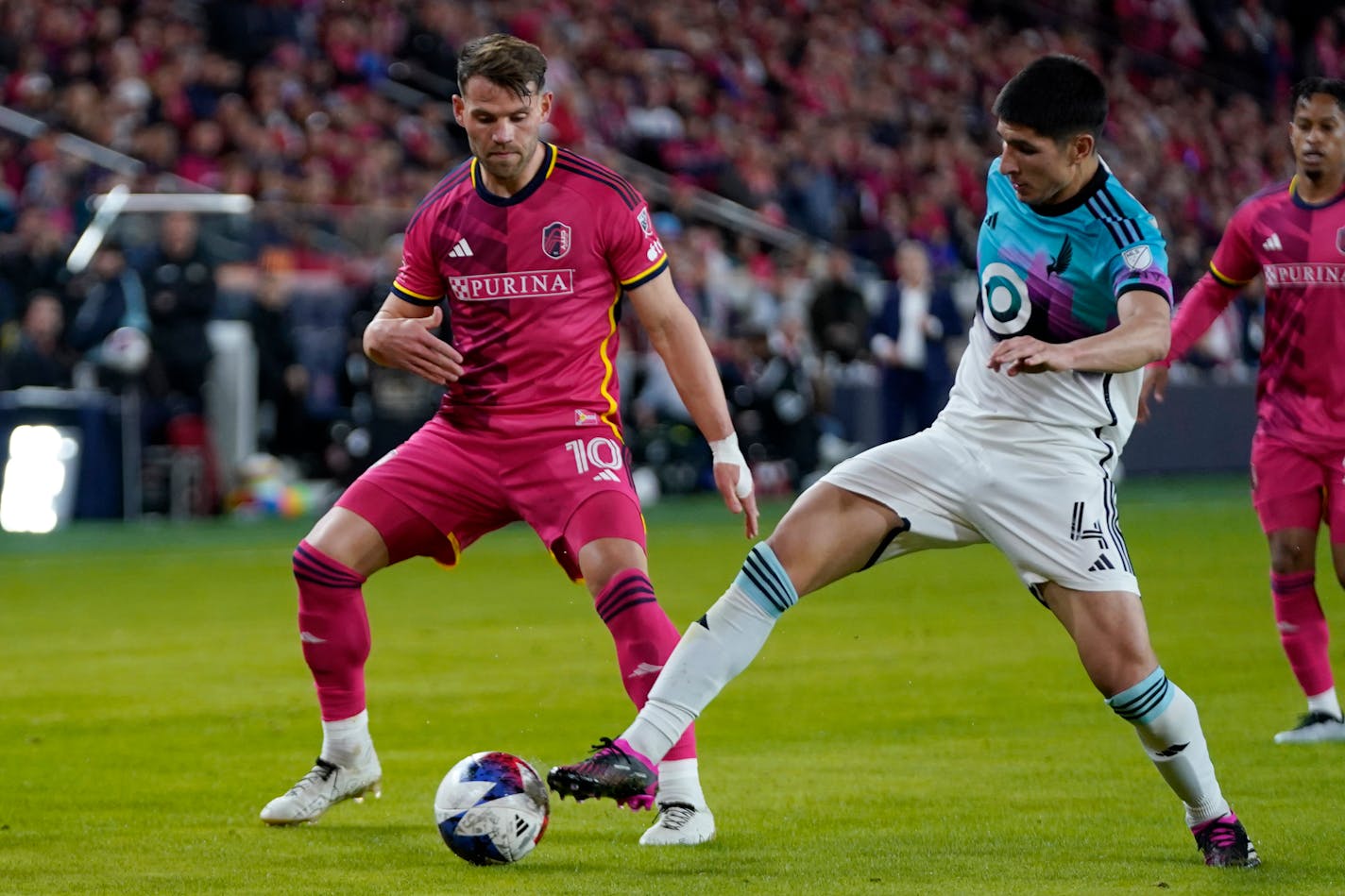 St. Louis City's Eduard Lowen (10) and Minnesota United's Miguel Tapias (4) battle for the ball during the second half of an MLS soccer match Saturday, April 1, 2023, in St. Louis. (AP Photo/Jeff Roberson)