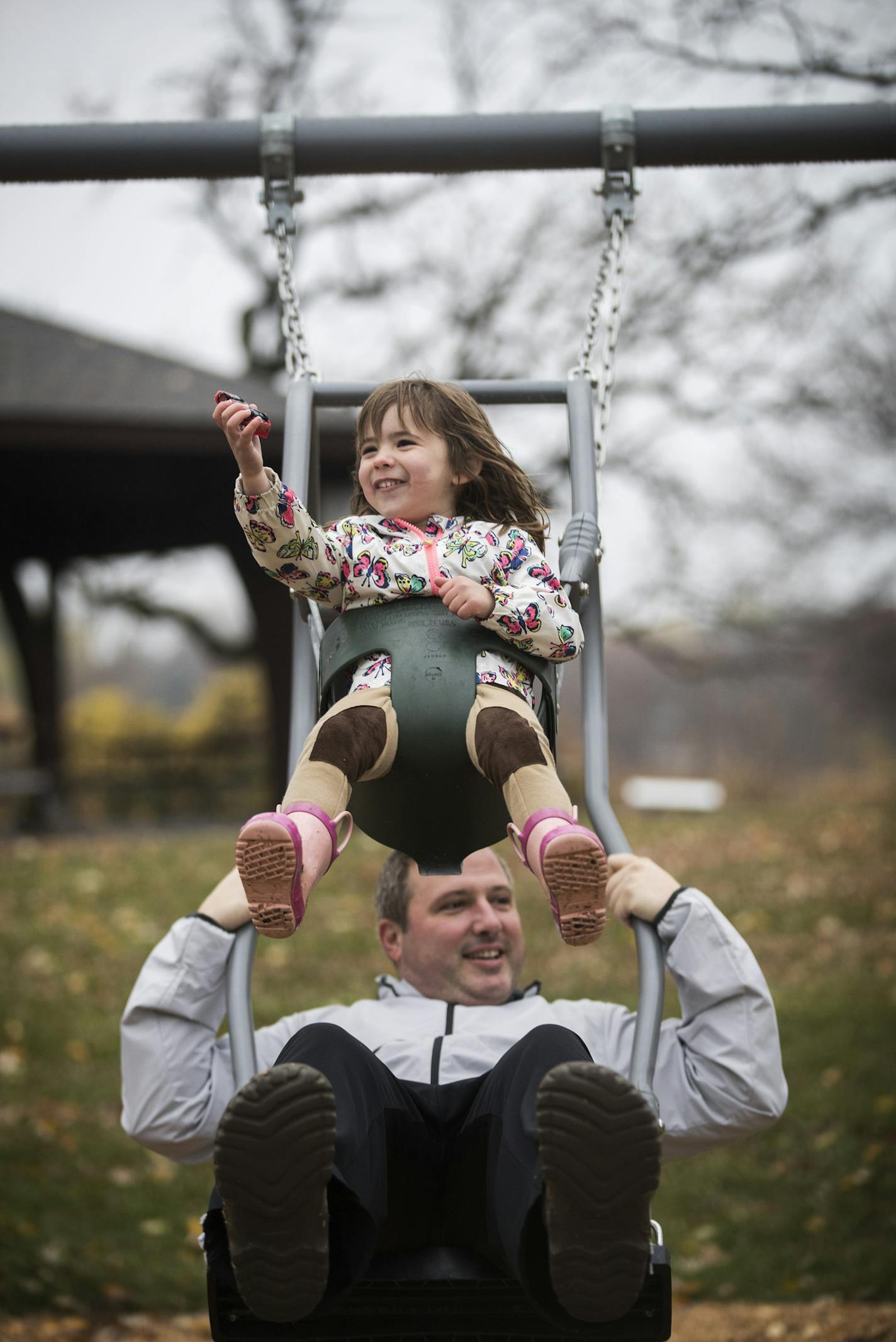 William Morrell and his daughter Macgregor, 3, swing on a dual swing, where an adult and child can swing together, at the new playground in Rosland Park in Edina. ] (Leila Navidi/Star Tribune) leila.navidi@startribune.com BACKGROUND INFORMATION: A ribbon cutting ceremony and grand opening of a universal playground at Rosland Park in Edina on Wednesday, October 26, 2016. A universal playground is opening in Edina, part of a recent trend by parents who want more accessible public equipment for chi