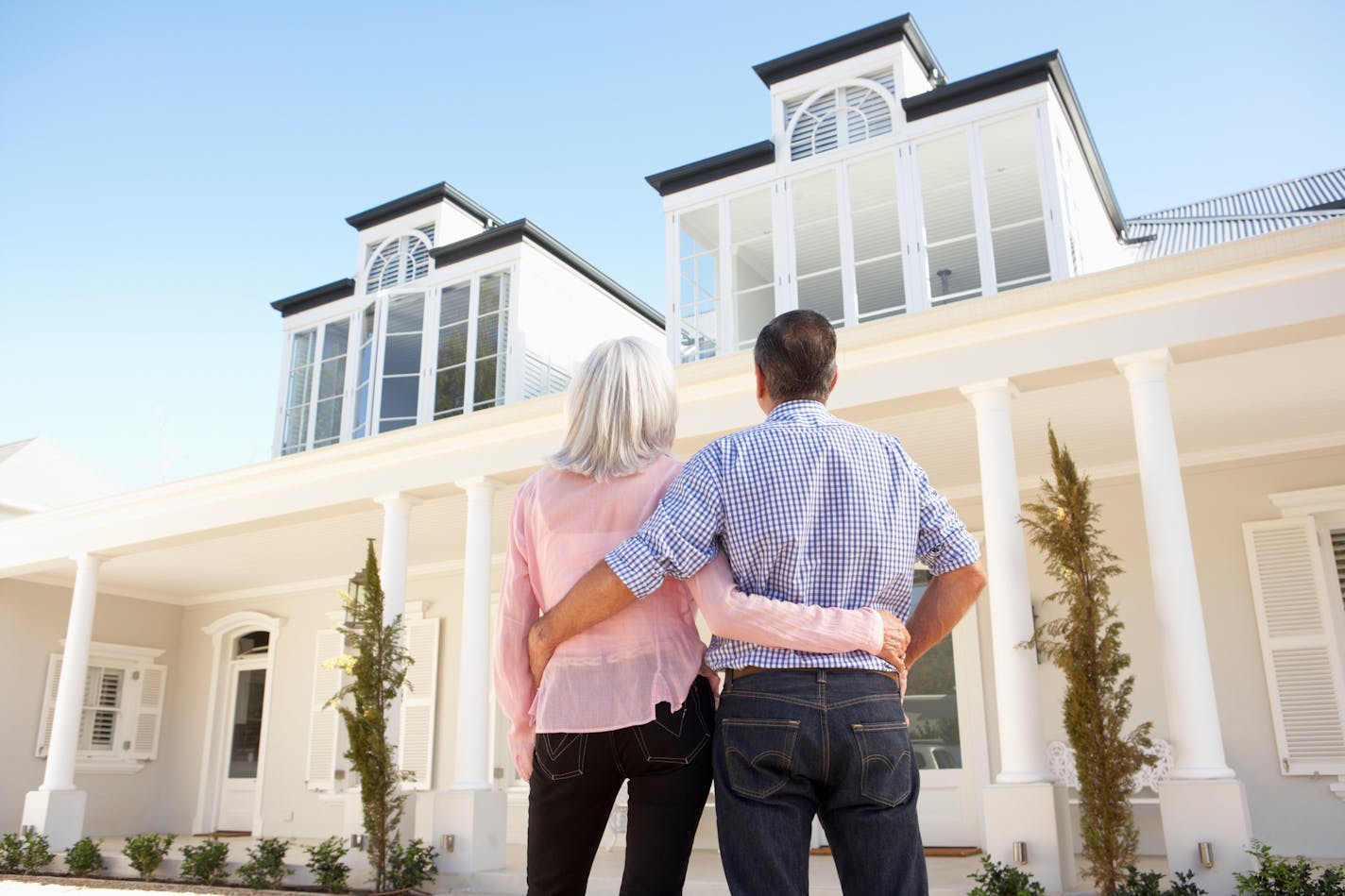 Senior Couple Standing Outside Dream Home.