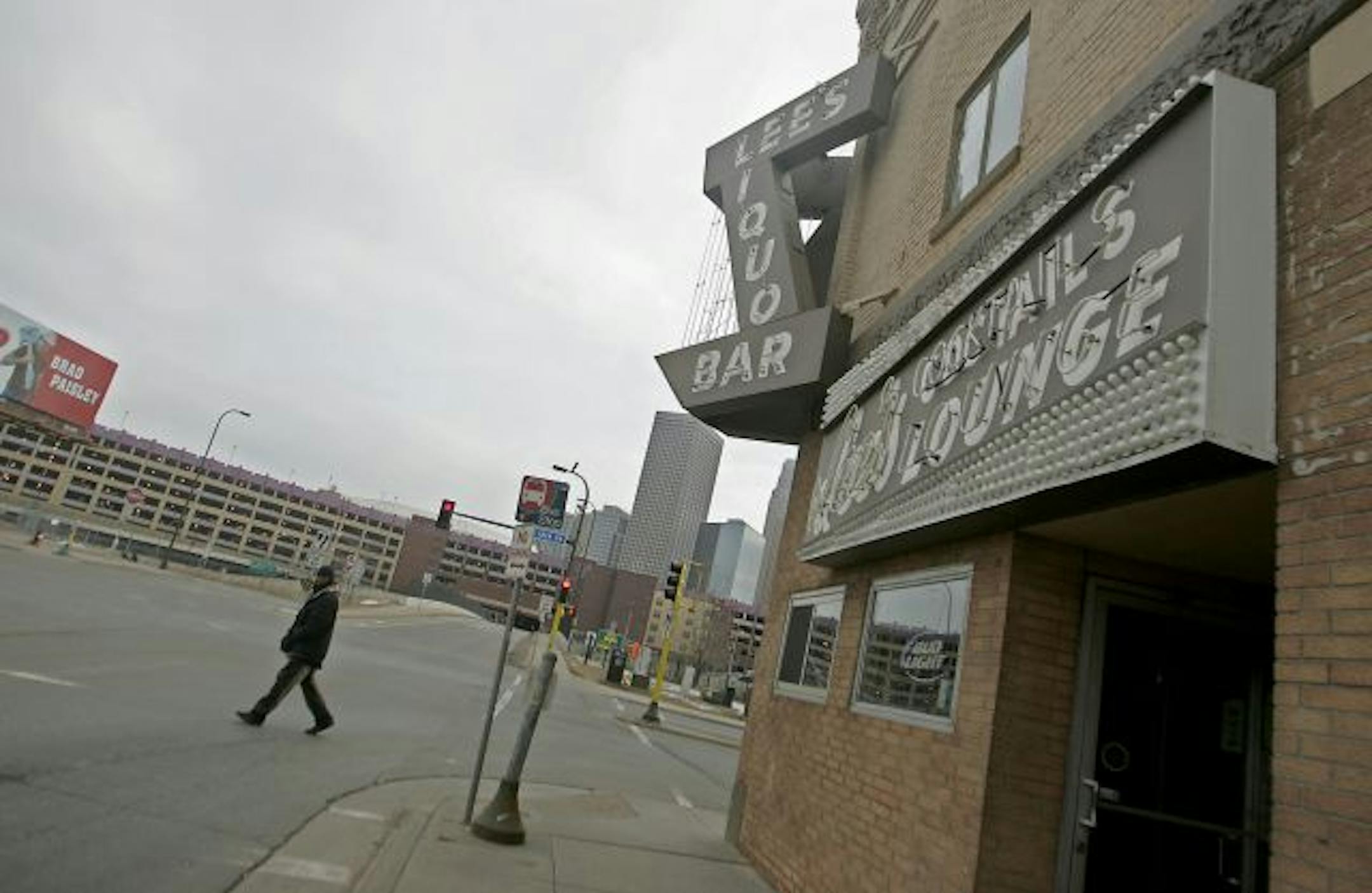 ELIZABETH FLORES � eflores@startribune.com February 13, 2009 - Minneapolis, MN - With the new Twins' stadium looming in the background, a pedestrian made his way near the famous Lee's Liquor Lounge. For Lee's Liquor Lounge owner, Lou Sirion, it looked like like the new twins stadium was going to be a blessing. Instead, it might be a mess. It looks like the twins are going to come and take his parking lot. Lee's is named after Sirion's wife.