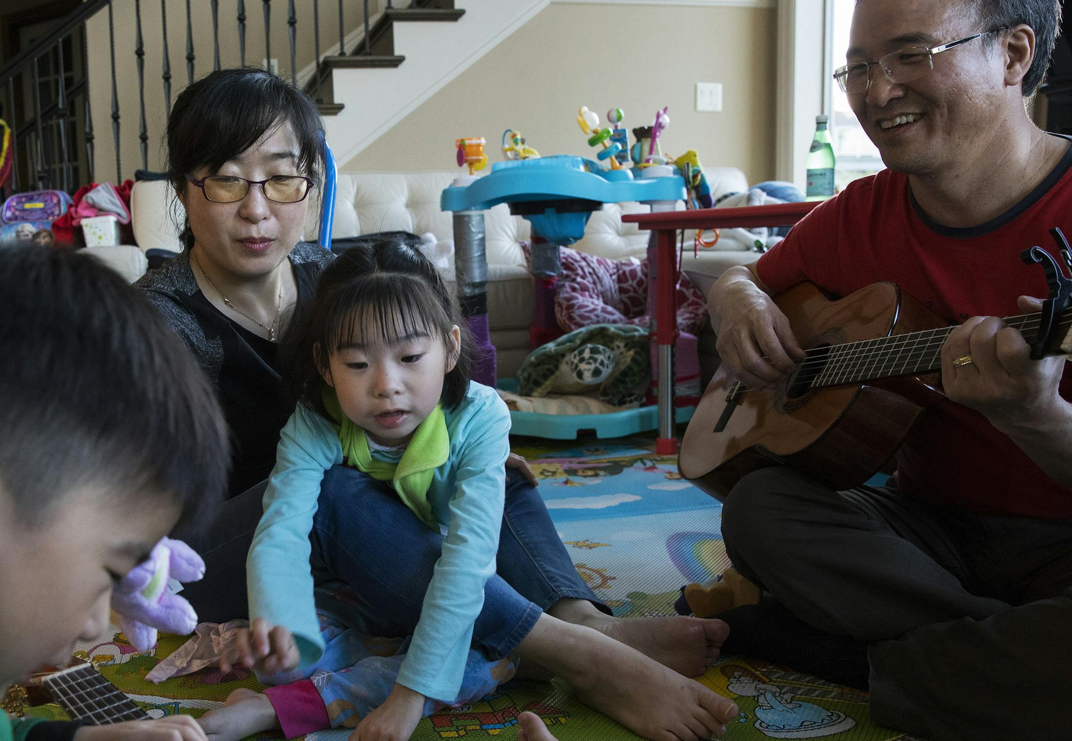 From left: Joon, 4, Soo-Kyung Lee, Yuna, 7, and Jae Lee spend time together with guitars at their home in Portland, Ore., May 23, 2017. Balancing the missions of science and motherhood, Soo-Kyung Lee, who had worked with the FOX family of genes for years, began doing what she is uniquely positioned to do: aiming her research squarely at her daughterís disorder. (Ruth Fremson/The New York Times)