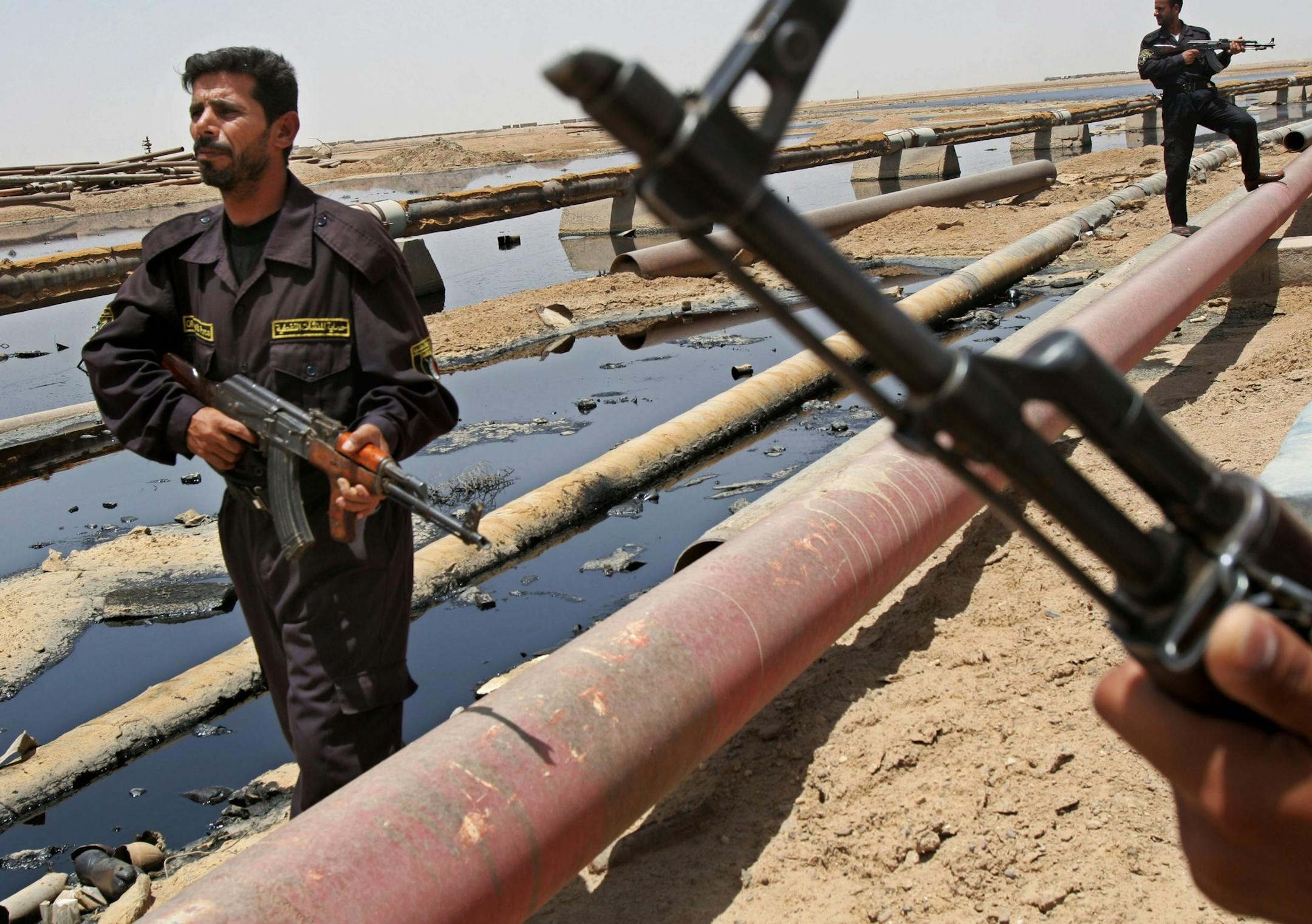 FILE - In this June 22, 2008 file photo, Iraqi police officers protecting oil installations secure an oil pipeline from the Rumailah refinery, north of Basra, Iraq. The turmoil in Iraq has thrown the OPEC memberís ambitious plans to boost oil production into doubt, threatening to crimp its most vital economic lifeline. Northern oil fields imperiled by the militantsí advance have been shut down, and companies have begun evacuating workers elsewhere in the country. Iraqís Kurdish mi