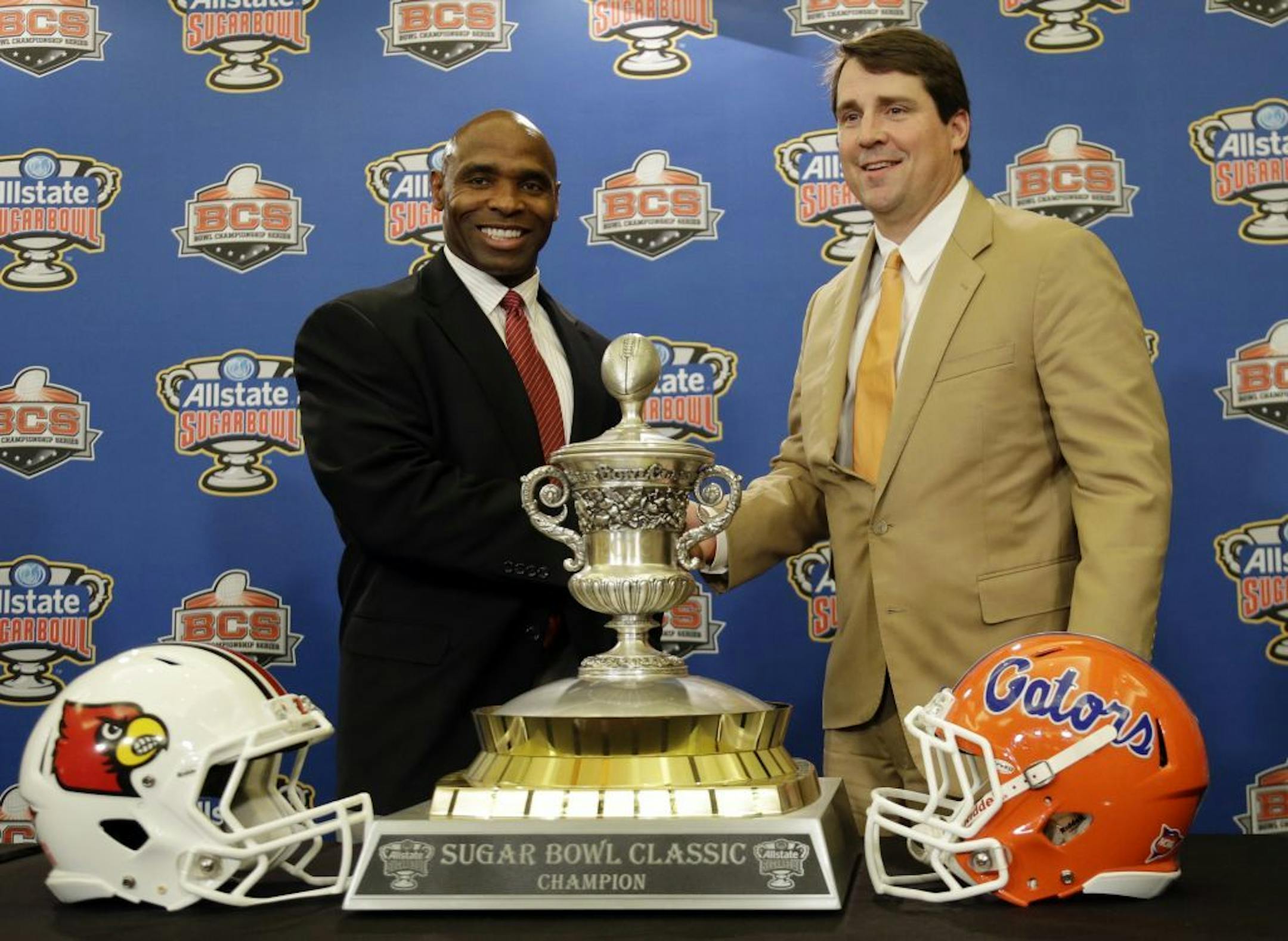 Louisville coach Charlie Strong, left, poses with the Sugar Bowl Trophy along with Florida coach Will Muschamp.