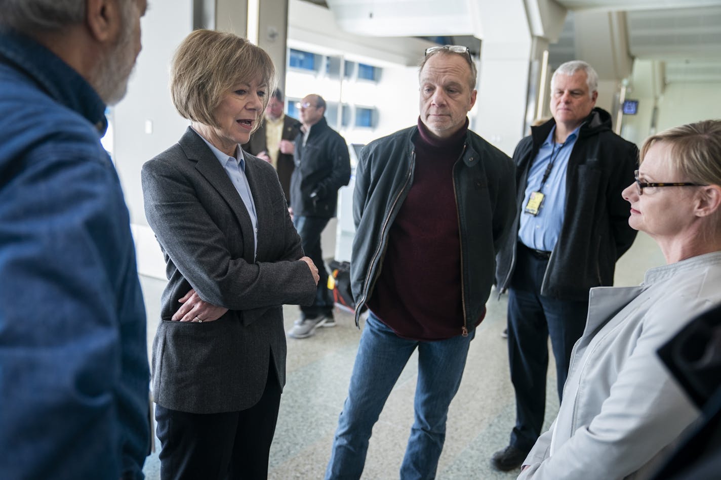 U.S. Sen. Tina Smith (D-Minn.), second from left, talks with Neal Gosman, from far left, Dennis Fuller-Rueschman, and Celia Hahn, all TSA workers who are currently going without pay.